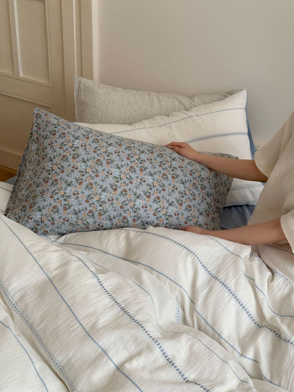 Person lying in bed with floral-patterned body pillow