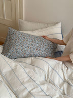 Person lying in bed with floral-patterned body pillow