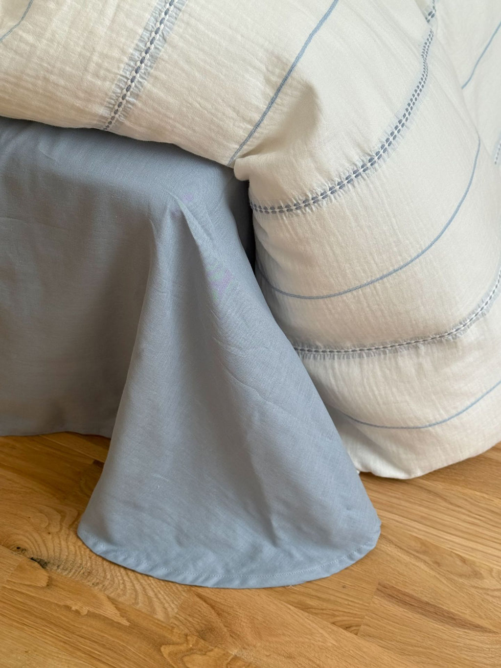 Light blue fabric draped over a wooden surface with a beige textured fabric in the background.