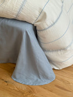 Light blue fabric draped over a wooden surface with a beige textured fabric in the background.