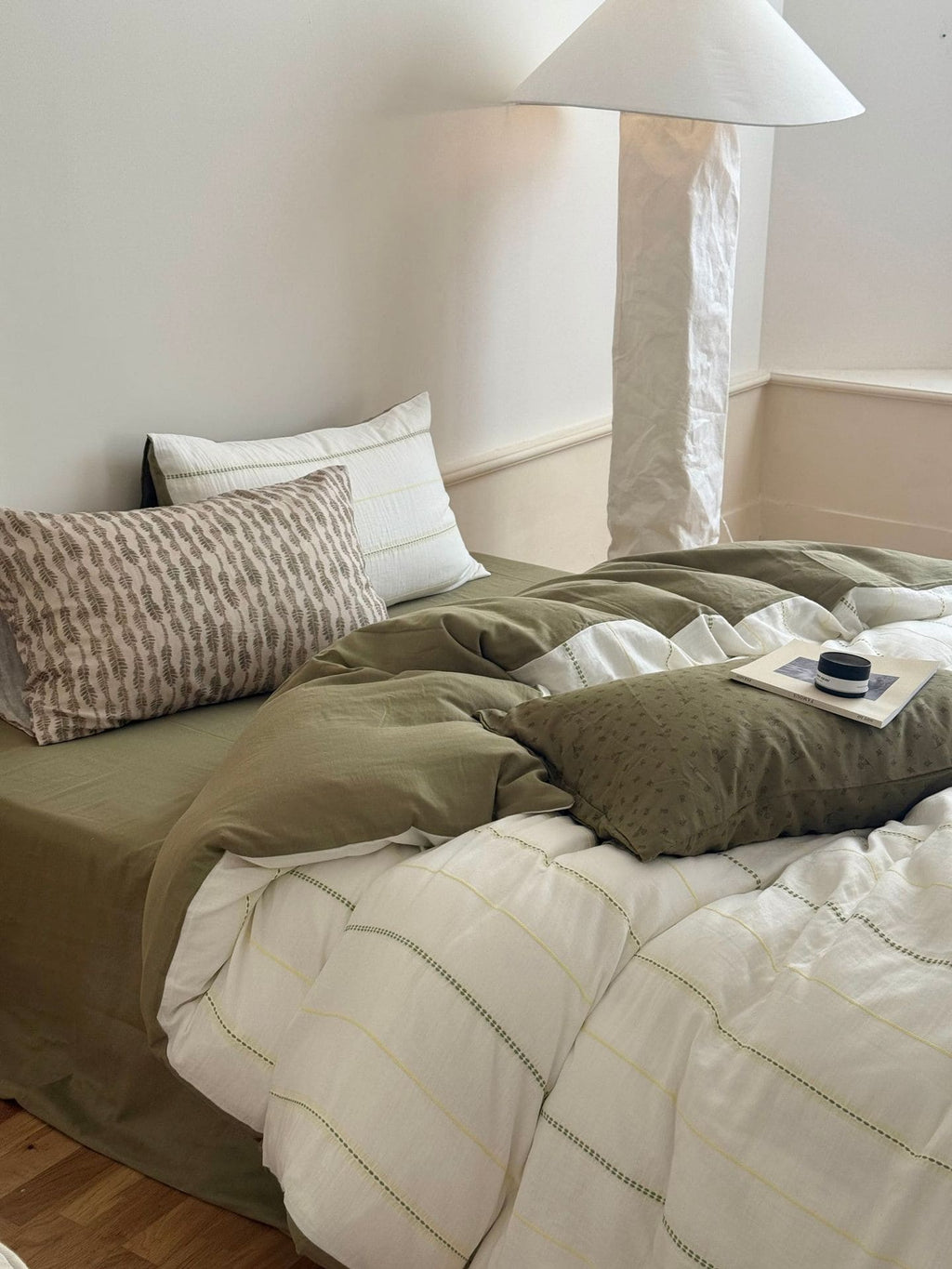 Bed with green bedding and pillows in a minimalist bedroom setting