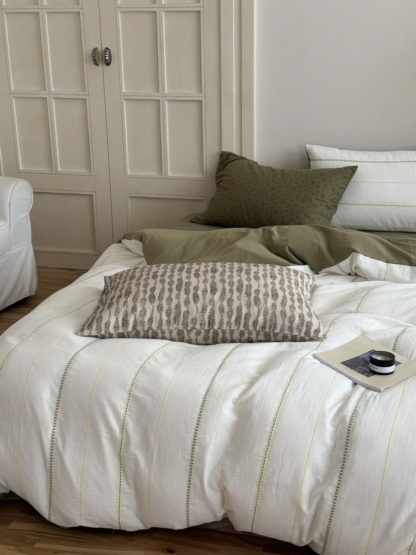 Green Bed with striped bedding and decorative pillows in a bedroom setting.