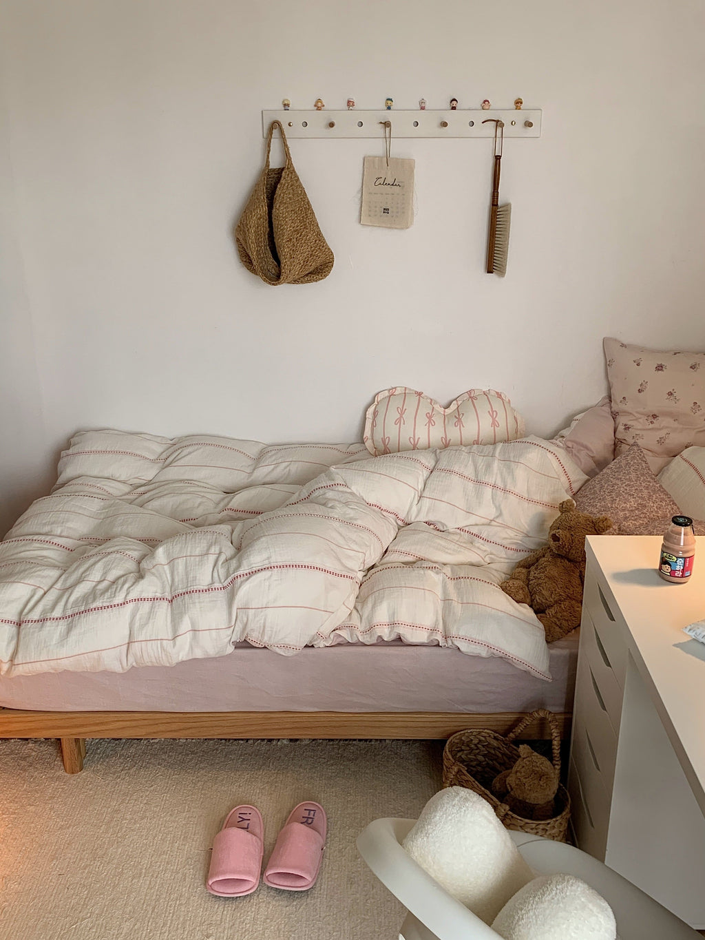 Bedroom with a Pink stripes duvet cover set, slippers, and a nightstand.