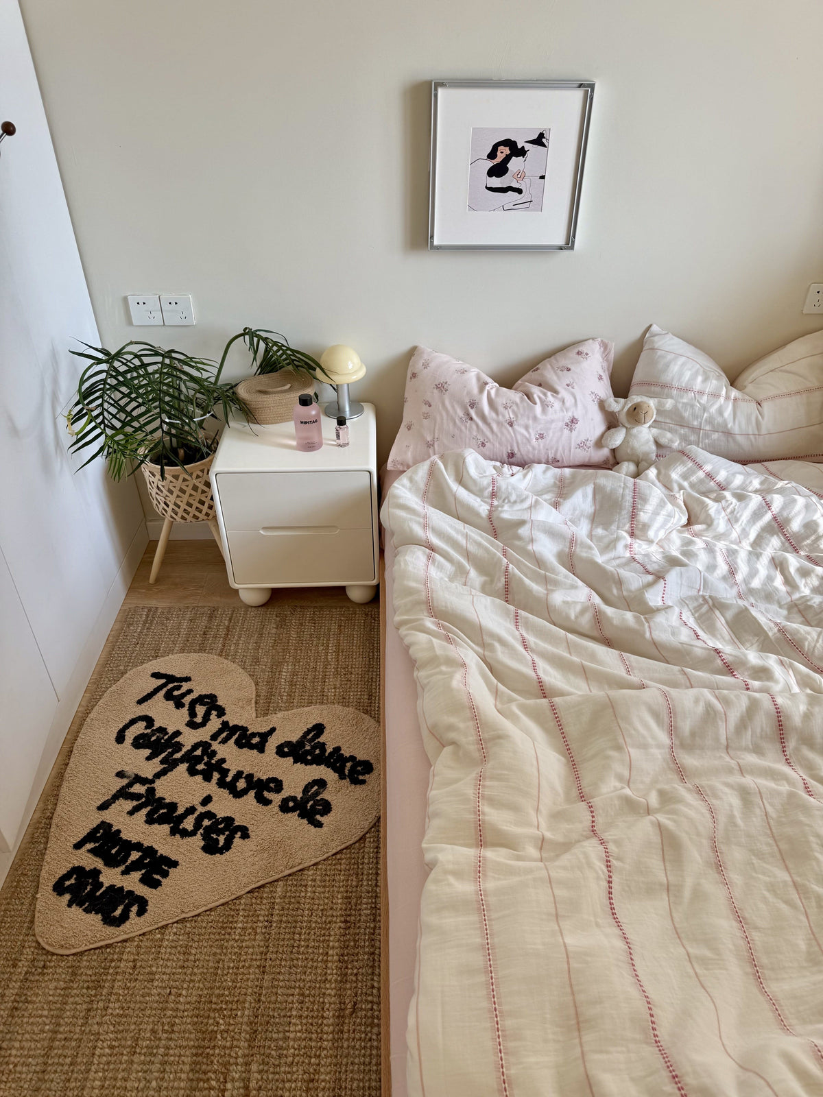 Pink Cute Bedroom with a bed, nightstand, and decorative items on a beige rug.