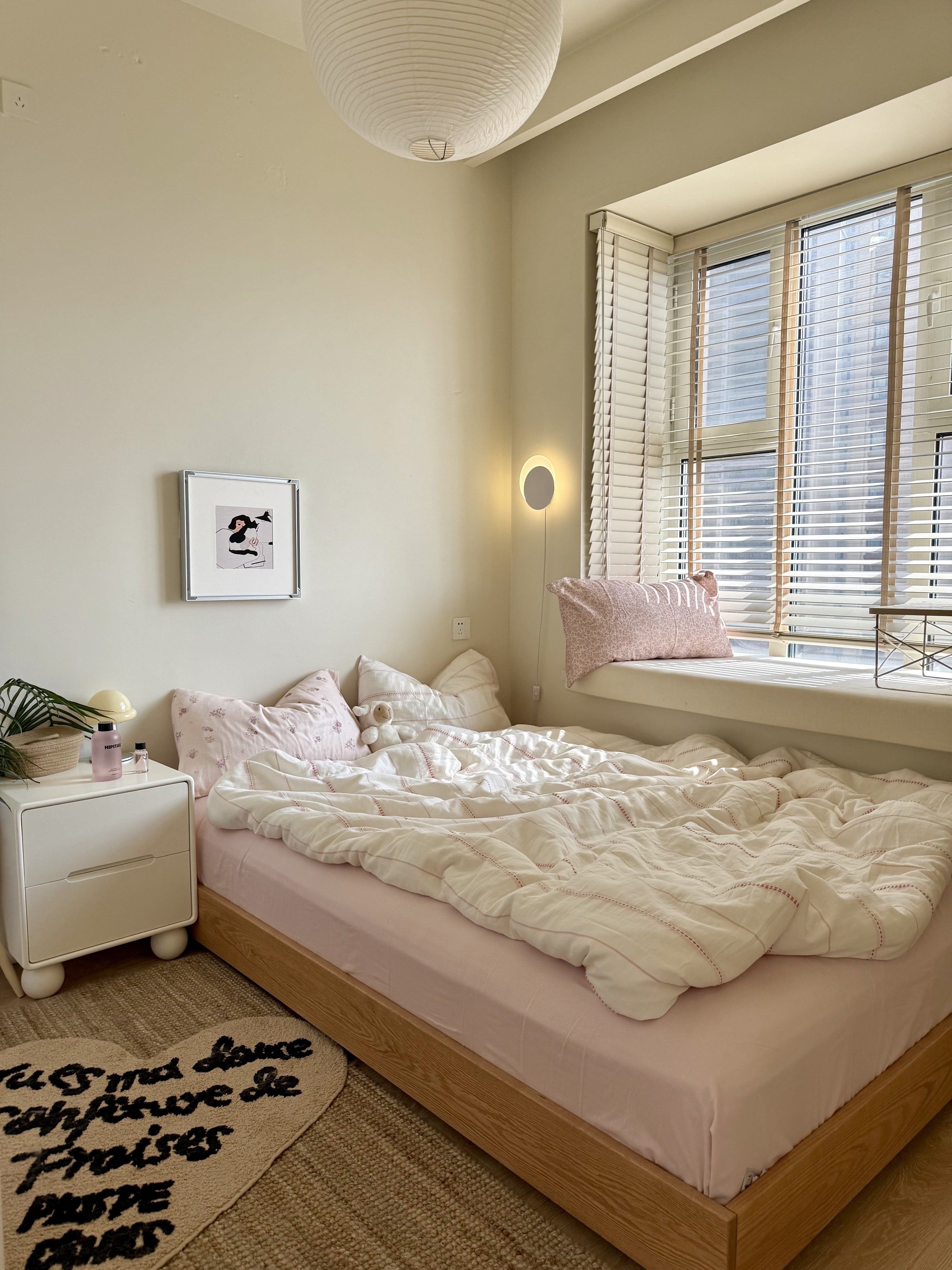 Cozy bedroom with a bed, nightstand, and window with blinds.