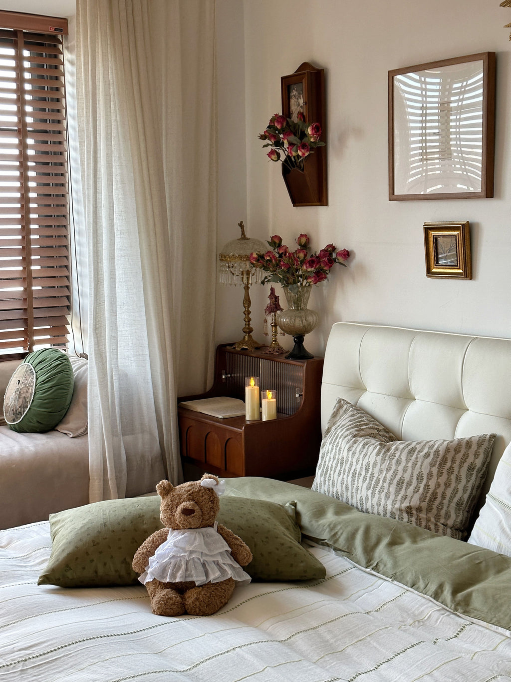 Bedroom with a teddy bear on a bed, candles on a nightstand, and decorative pillows.