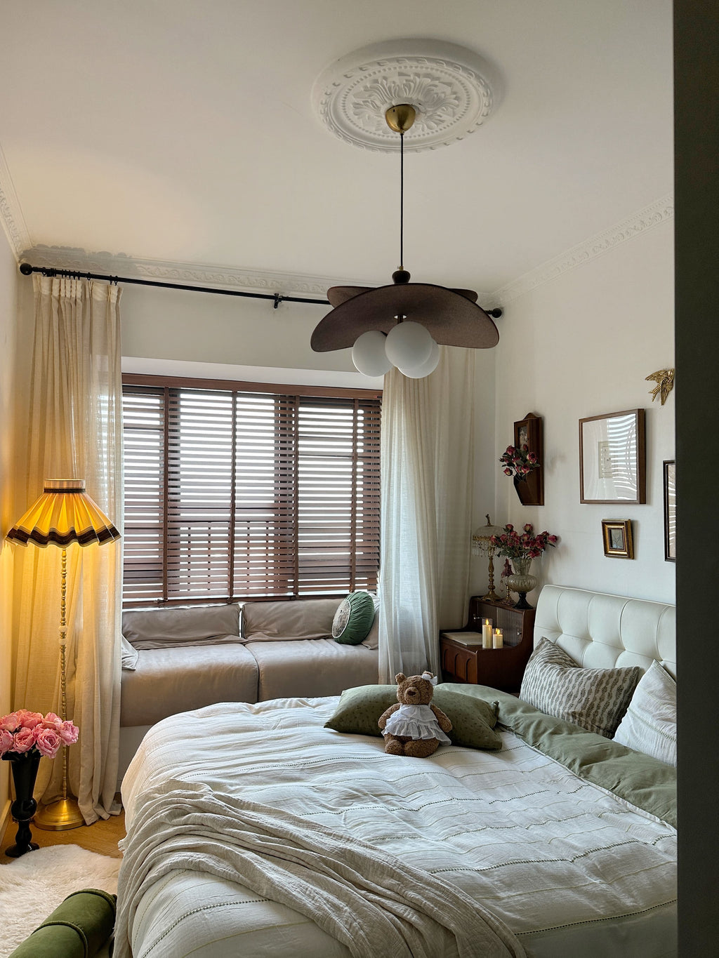 Neatly made bed in a bedroom with a lamp, sofa, and decor items.